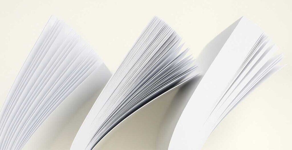 Close-up photo of several open stacks of white paper showing varying thickness and textures, demonstrating differences in paper weight and finish.